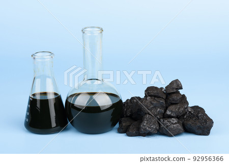 Crude oil in glass beakers and black hard coal lumps on blue background, fossil fuel concept 92956366