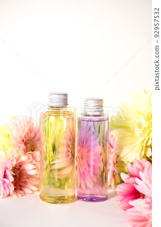 Plastic containers with pink and yellow liquids lined up in the middle of a flower 92957532