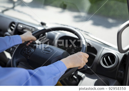 Hands of a young female driver holding the steering wheel of a truck Hands of a young female driver holding the steering wheel of a truck 92958350