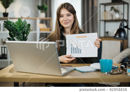 Young woman freelance showing graphs and chart while sitting at table. 92958838