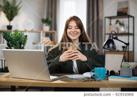 Confident young woman writing message during mobile conversation at office. Confident young woman writing message during mobile conversation at office. 92958966