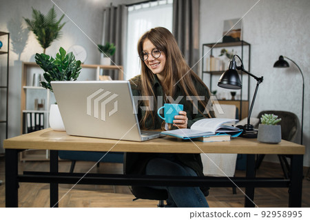 Young excited woman sitting at workplace with portable computer and document. Young excited woman sitting at workplace with portable computer and document. 92958995