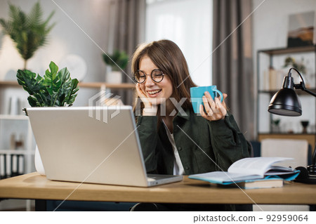 Happy laughing woman talking and smiling during video chat on modern laptop. Happy laughing woman talking and smiling during video chat on modern laptop. 92959064