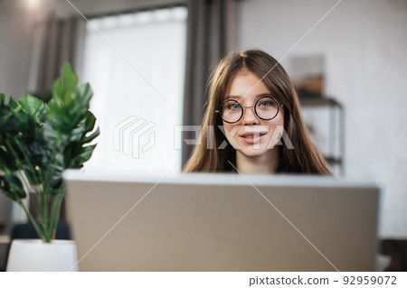 Female freelancer in casual shirt using computer for remote work. Female freelancer in casual shirt using computer for remote work. 92959072
