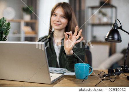 Beautiful caucasian woman with long dark hair sitting at desk and typing on laptop. Beautiful caucasian woman with long dark hair sitting at desk and typing on laptop. 92959082