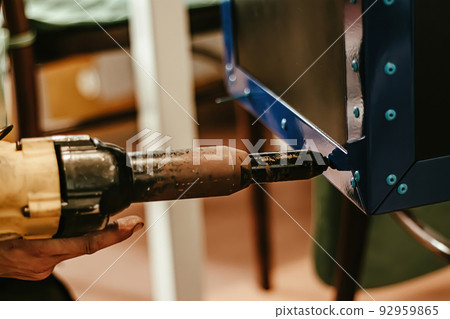 Male worker uses electric riveting gun. Hand holding  riveting m 92959865
