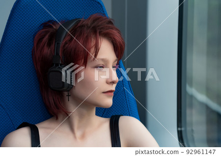 young woman listening to music with headphones while riding on a high-speed train 92961147