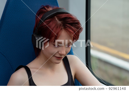 young woman listening to music with headphones while riding on a high-speed train 92961148