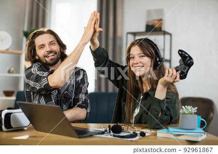 Cheerful couple of friends, boy and girl, giving high five each other while celebrating success Cheerful couple of friends, boy and girl, giving high five each other while celebrating success 92961867