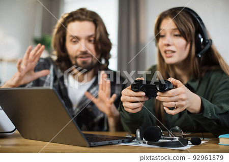 Man and pretty blond woman, sitting and embracing together, playing video games using joystick Man and pretty blond woman, sitting and embracing together, playing video games using joystick 92961879