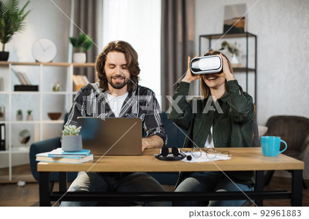 Happy young friends sitting at the table and using modern gadgets for work or study. 92961883