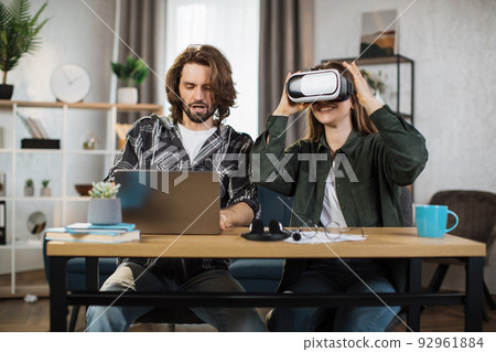 Happy young friends sitting at the table and using modern gadgets for work or study. 92961884