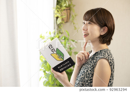 Woman smiling and holding an investment book 92963294