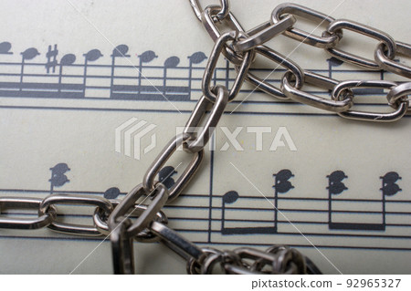 Metal chain placed on paper with musical notes Metal chain placed on paper with musical notes 92965327