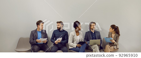 Multiracial people men and women waiting in line for interview at large company sits near wall Multiracial people men and women waiting in line for interview at large company sits near wall 92965910