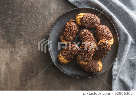 Petit fours with chocolate sprinkles. Mini chocolate dessert on plate. 92966303