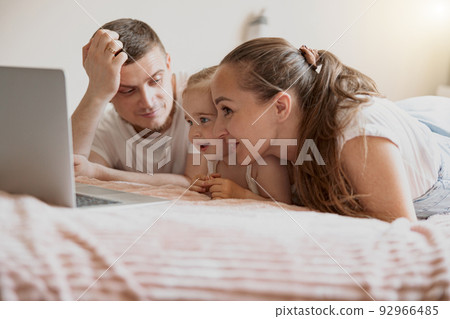 Cheerful family having fun together watching cartoons online on laptop lie on sofa at home 92966485