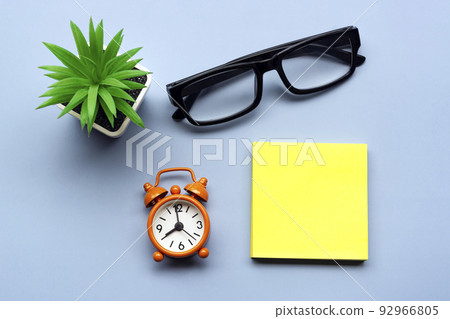 Adhesive Note with potted plant and alarm clock set at 8 o'clock. Copy space. Adhesive Note with potted plant and alarm clock set at 8 o'clock. Copy space. 92966805