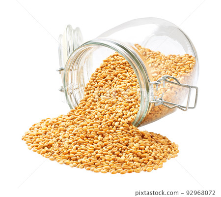 Raw organic wheats spill out of a glass storage jar isolated on white background. 92968072