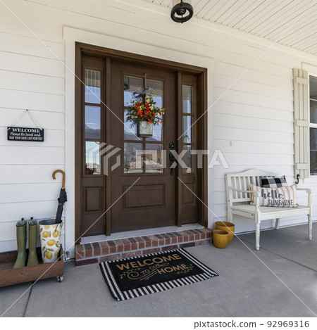 Square Porch of a house with bench and wooden rack with boots and umbrella Square Porch of a house with bench and wooden rack with boots and umbrella 92969316