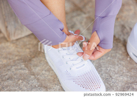 Woman tying shoelaces on sneakers Woman tying shoelaces on sneakers 92969424