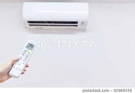 Air conditioner, room temperature 28 degrees when cooling, woman's hand operating the remote control Air conditioner, room temperature 28 degrees when cooling, woman's hand operating the remote control 92969558