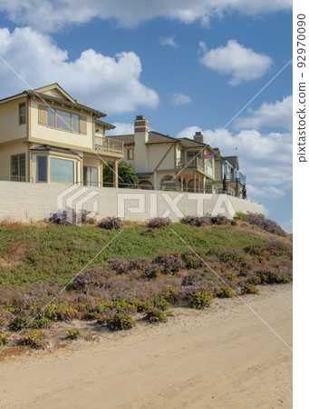 Vertical White puffy clouds Dirt road outside the fenced beach houses at Carlsbad, Californi 92970090