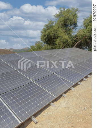 Vertical White puffy clouds Ground-mounted solar panels on a large field of botanical garden 92970097