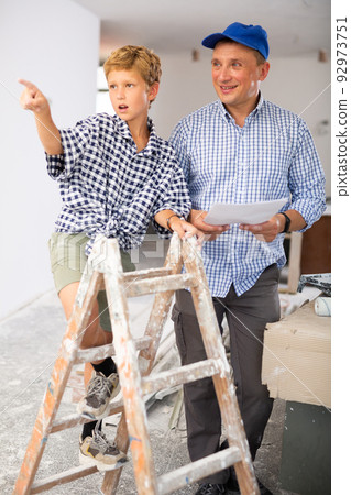 Man showing son blueprints in new home Man showing son blueprints in new home 92973751