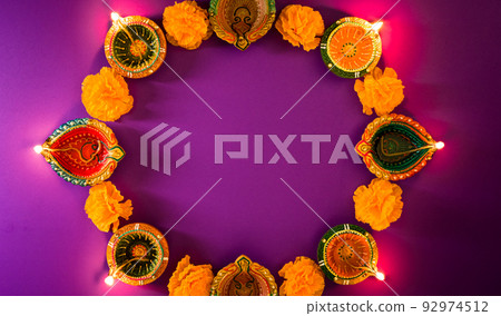 Happy Diwali - Clay Diya lamps lit during Dipavali, Hindu festival of lights celebration. Colorful traditional oil lamp diya on purple background Happy Diwali - Clay Diya lamps lit during Dipavali, Hindu festival of lights celebration. Colorful traditional oil lamp diya on purple background 92974512