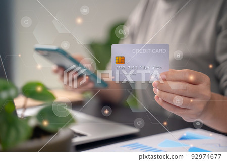 Close up shot of females hands holding credit card typing message on smart phone with technology icons for shopping online. Close up shot of females hands holding credit card typing message on smart phone with technology icons for shopping online. 92974677