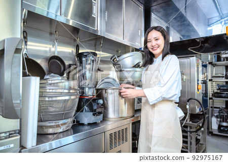 一位年輕女子介紹餐廳廚房大火鍋 一位年輕女子介紹餐廳廚房大火鍋 92975167