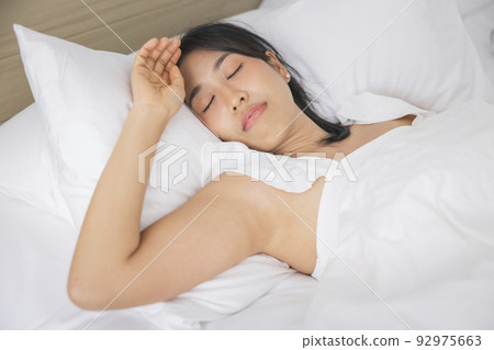Young asian woman sleeping in bed at bedroom. she is lying on side and relax with eyes closed 92975663