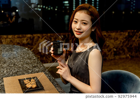 享受烤雞肉串和清酒的女人 92975944