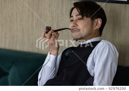 Handsome man smoking a pipe tobacco Handsome man smoking a pipe tobacco 92976200