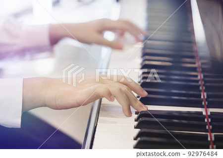 Elementary school girl playing piano Elementary school girl playing piano 92976484