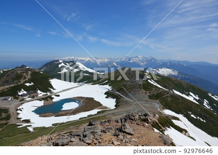 Tsurugaike Pond and Hida Mountains with residual snow seen from Mount Fujimi in Norikura 92976646