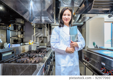 A woman wearing a white coat in a restaurant kitchen 92977060