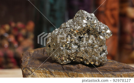 Pyrite Specimen on Raw Tigers Eye Rock With Dried Herbs in Background 92978127