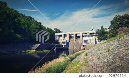 A dam on the Brno Reservoir by the Svratka River with a small power plant. Beautiful sunny summer day in nature. A dam on the Brno Reservoir by the Svratka River with a small power plant. Beautiful sunny summer day in nature. 92979514