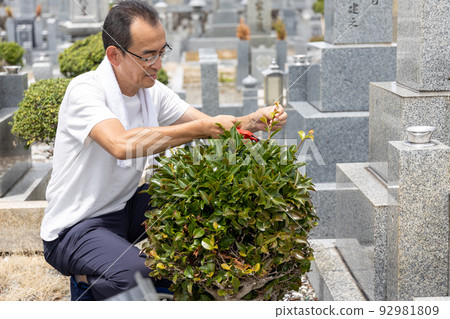 A senior man who comes to visit the grave and takes care of the plants in the grave A senior man who comes to visit the grave and takes care of the plants in the grave 92981809