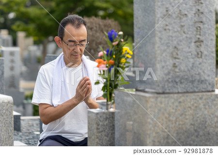 一位老人來掃墓,將手放在清理墳墓後已經清理過的墳墓上 一位老人來掃墓,將手放在清理墳墓後已經清理過的墳墓上 92981878