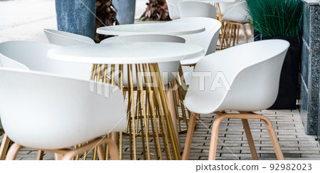Street cafe with white chairs, green foliage around. Without people, tourism, travel. 92982023