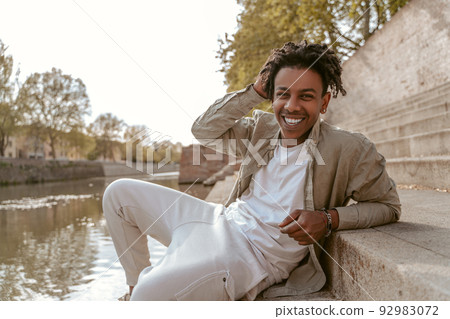 Guy smiling at camera resting near water Guy smiling at camera resting near water 92983072