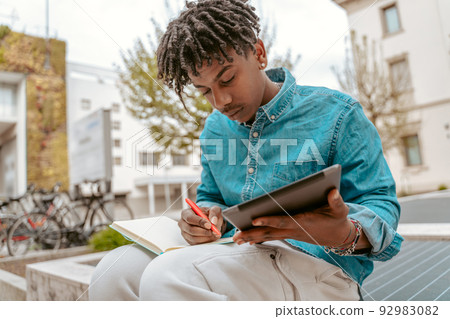 Guy with tablet writing with pen in notebook Guy with tablet writing with pen in notebook 92983082