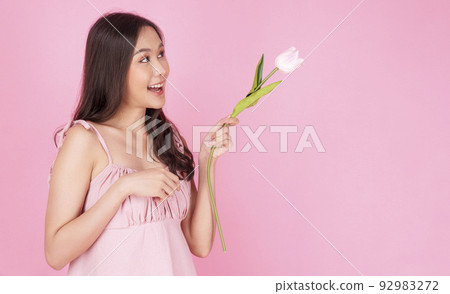 Satisfied excited asian woman holding tulips pointing up wonder to copy space smiling with toothy Satisfied excited asian woman holding tulips pointing up wonder to copy space smiling with toothy 92983272