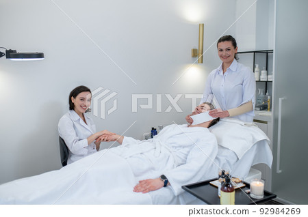 Young man having hand massage and face procedures in the salon Young man having hand massage and face procedures in the salon 92984269