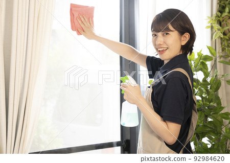 House cleaning female worker wiping the window House cleaning female worker wiping the window 92984620