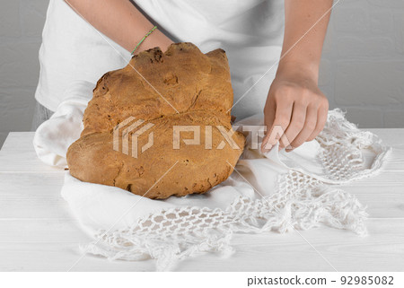 Female hands putting the bread of Matera, Pane di Matera on white background, typical southen italian sourdough bread 92985082