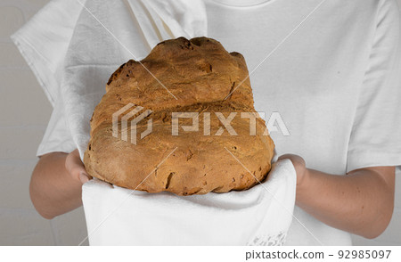 Female hands holding the bread of Matera, Pane di Matera on white background, typical southen italian sourdough bread 92985097